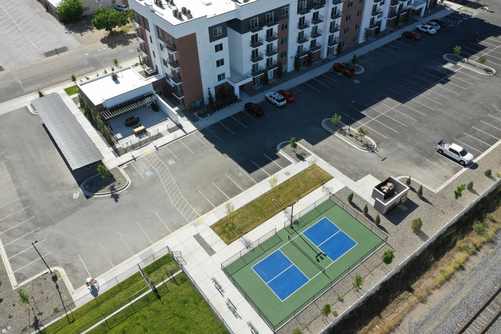 Aerial view of a modern apartment complex with pickleball courts and parking.