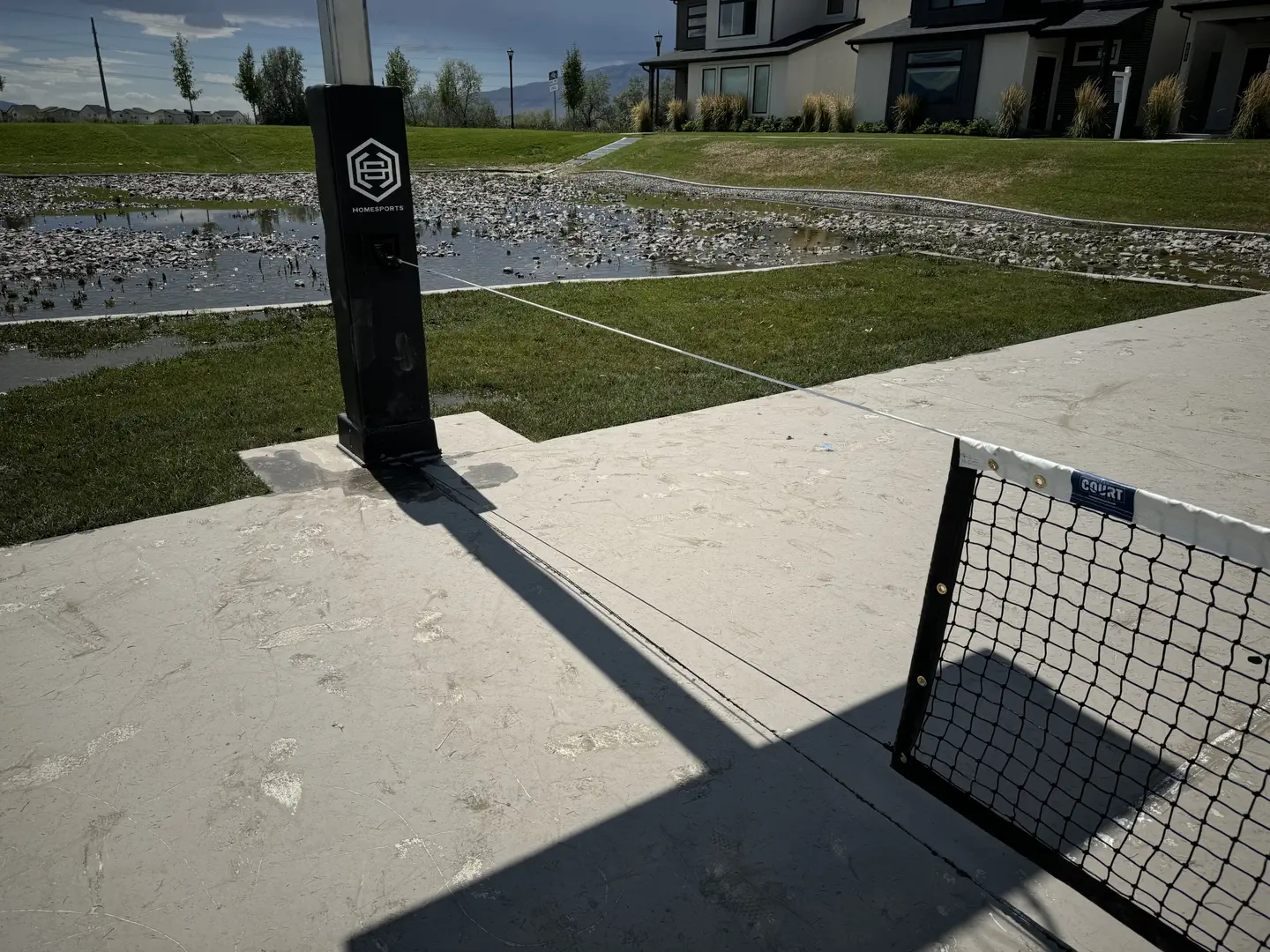 HomeSports pickleball net setup with a flooded area in the background.