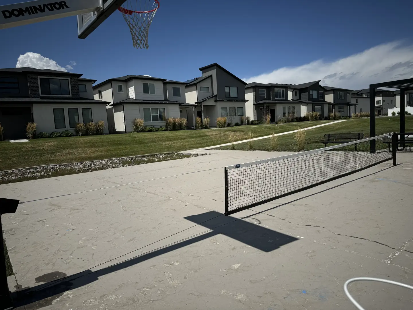 Modern townhouses with a basketball hoop and tennis net in a suburban neighborhood.