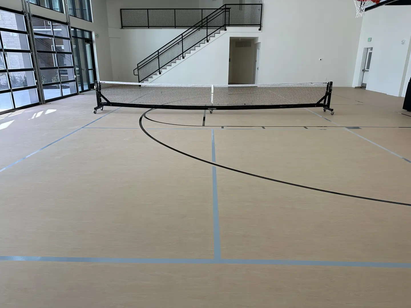Indoor pickleball court with net and basketball hoop