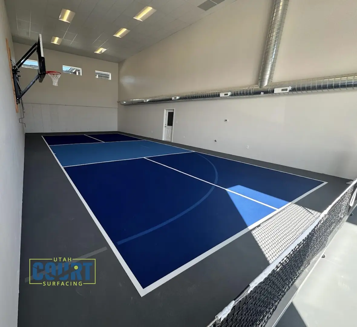 Indoor multi-sport court in Utah with blue surfacing and basketball hoop.