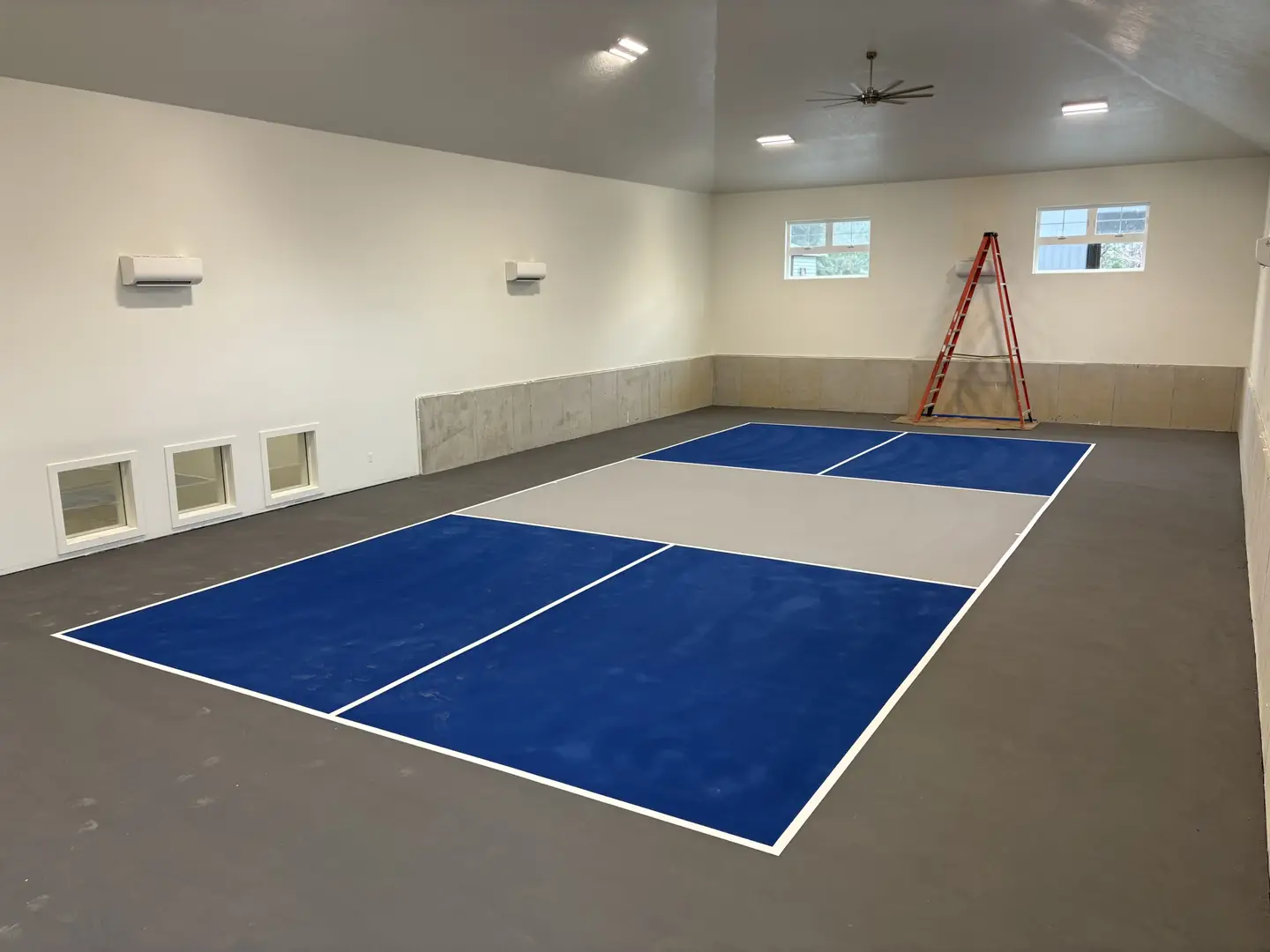Indoor pickleball court with blue and gray playing surface.
