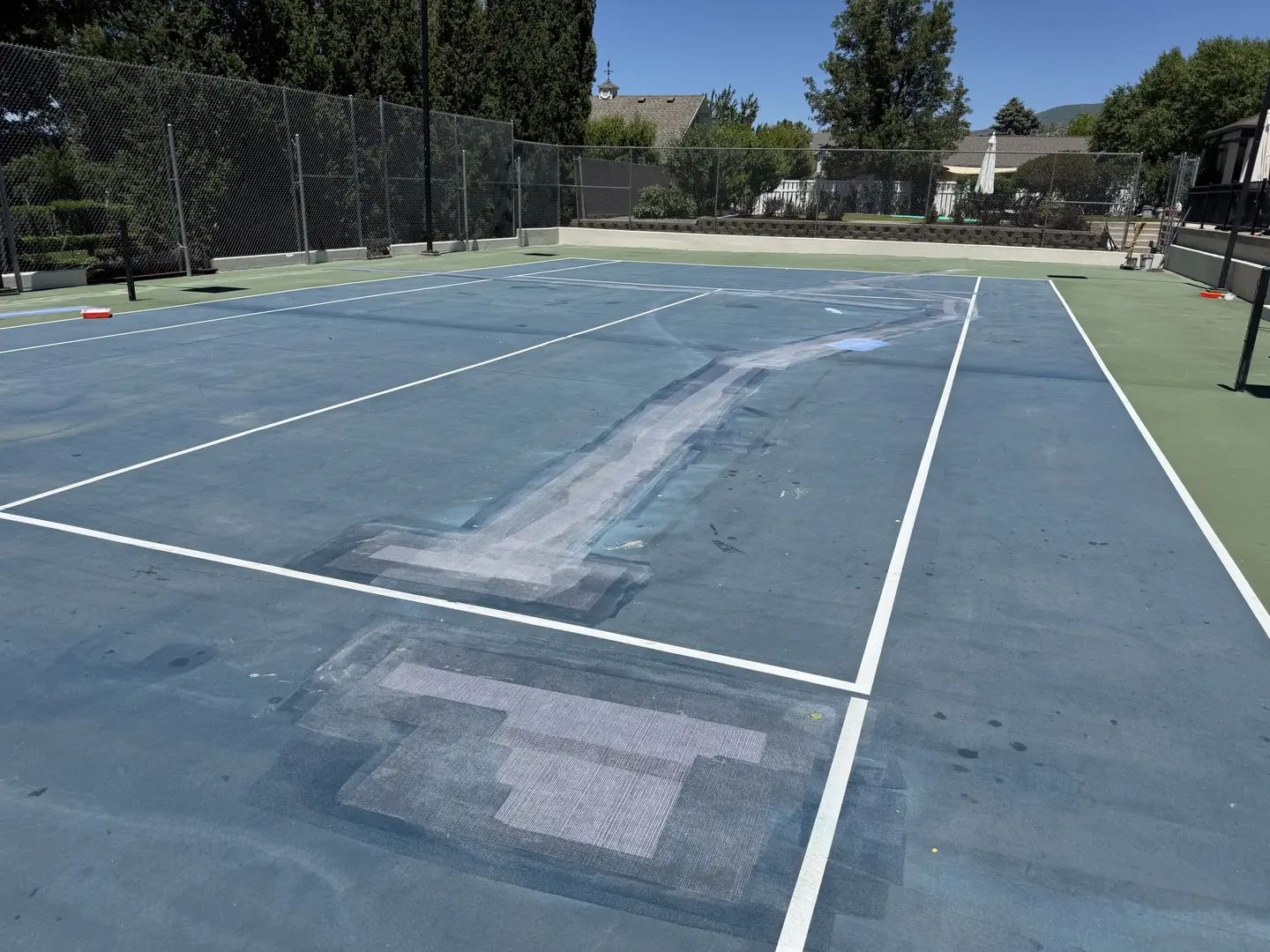 Tennis court with patched areas and white lines