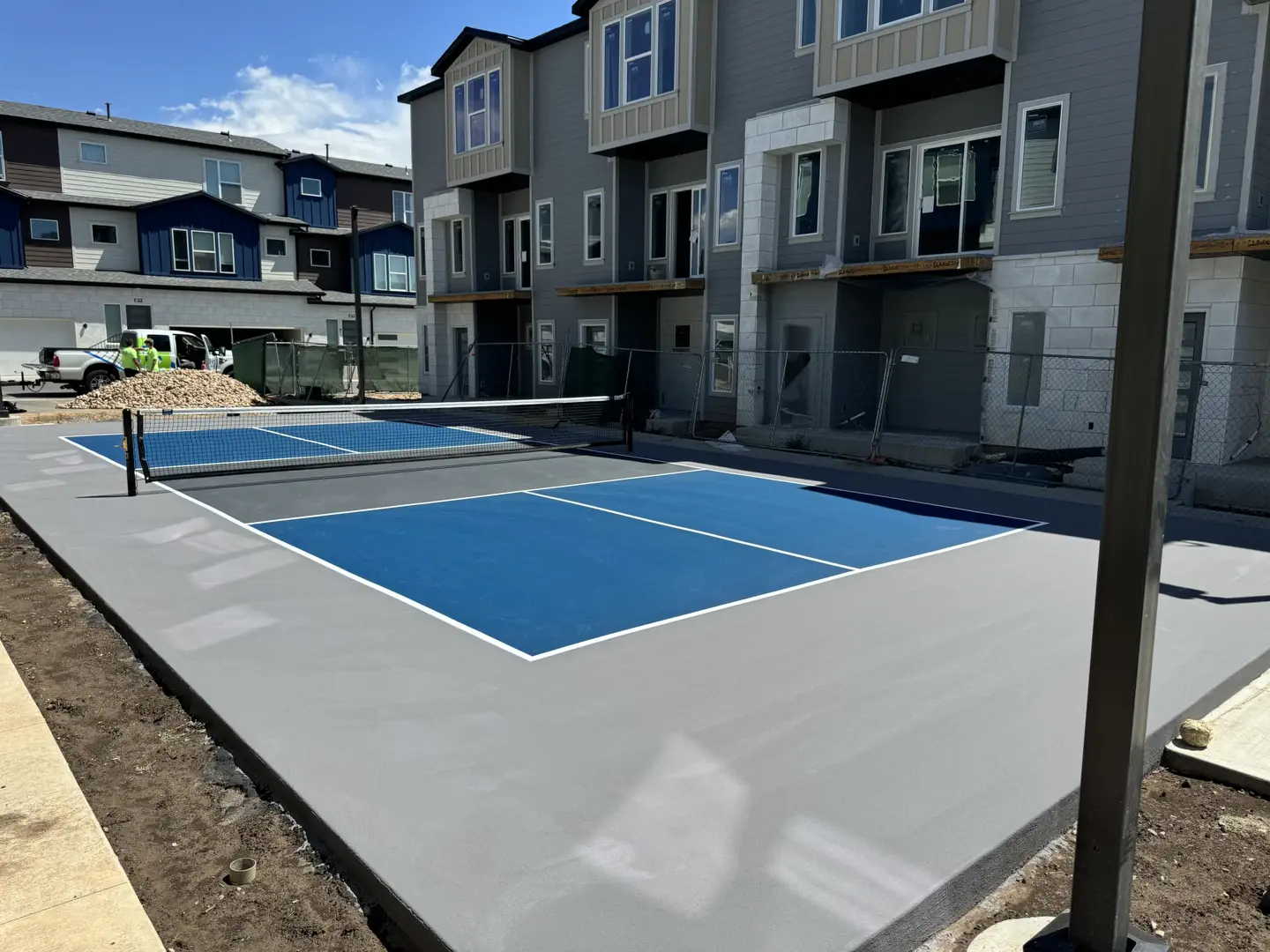 New pickleball court construction with modern townhomes in background.
