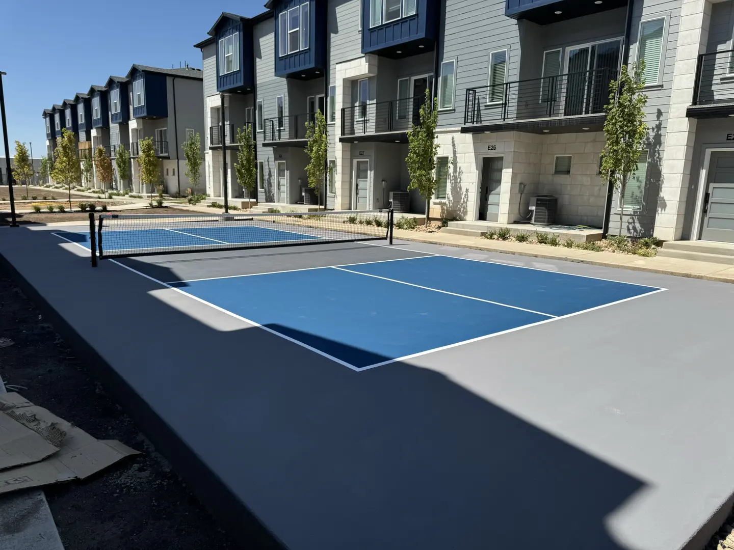 New blue pickleball court next to modern townhomes