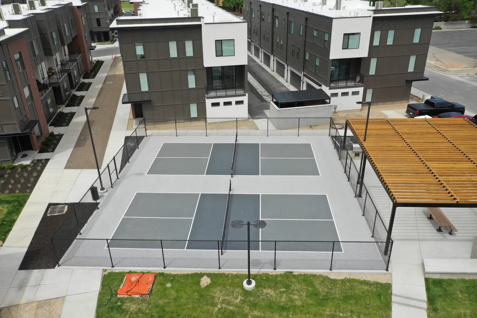 Modern apartment complex with pickleball courts and outdoor amenities.