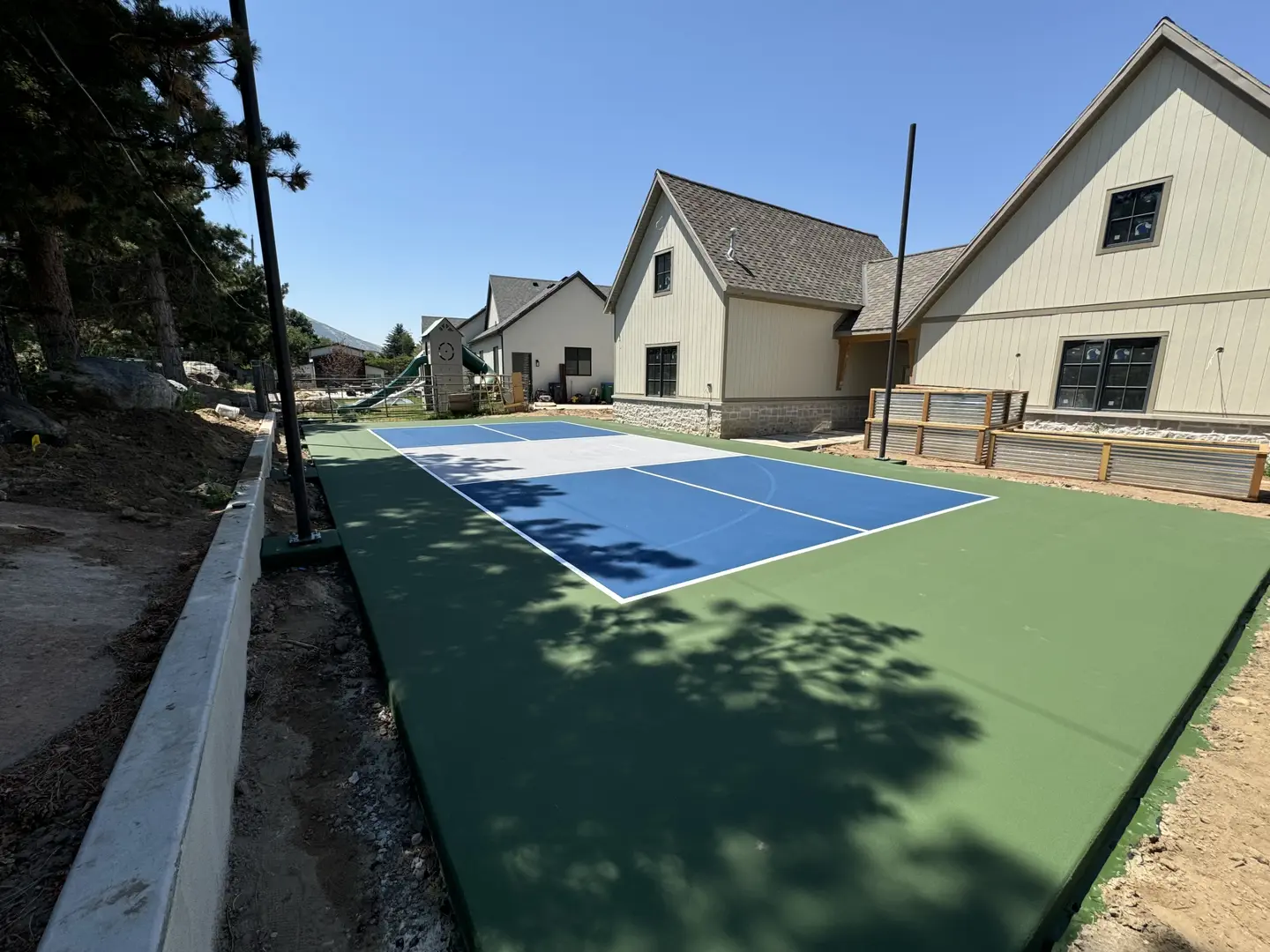 Newly installed blue and white pickleball court with green surround.