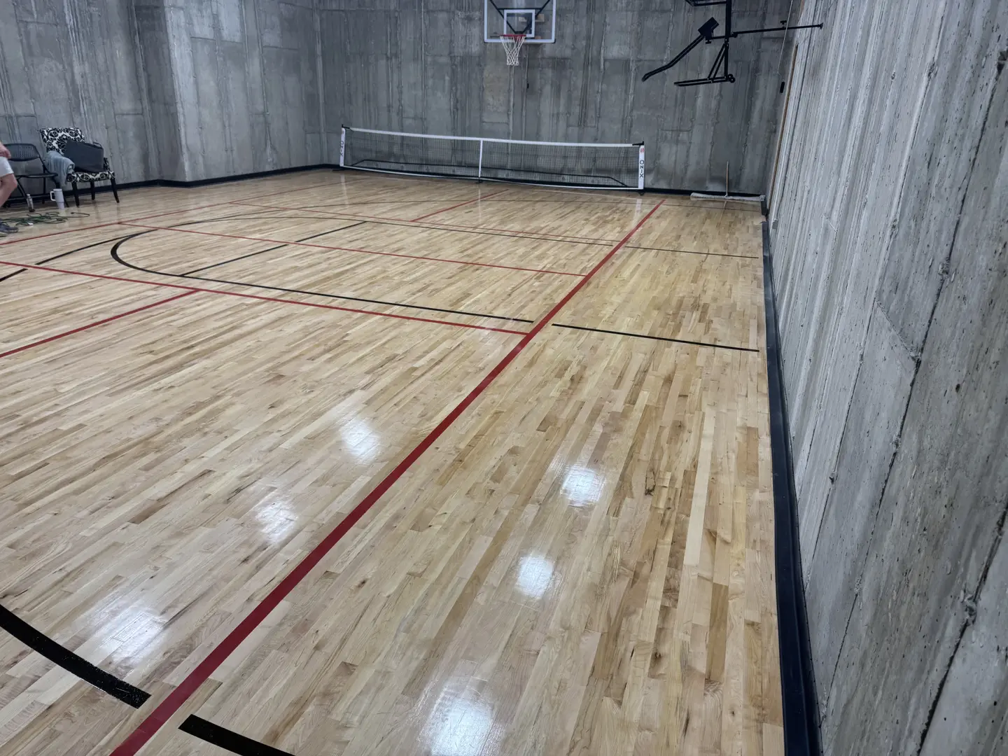 Indoor basketball court with wooden floor and concrete walls.