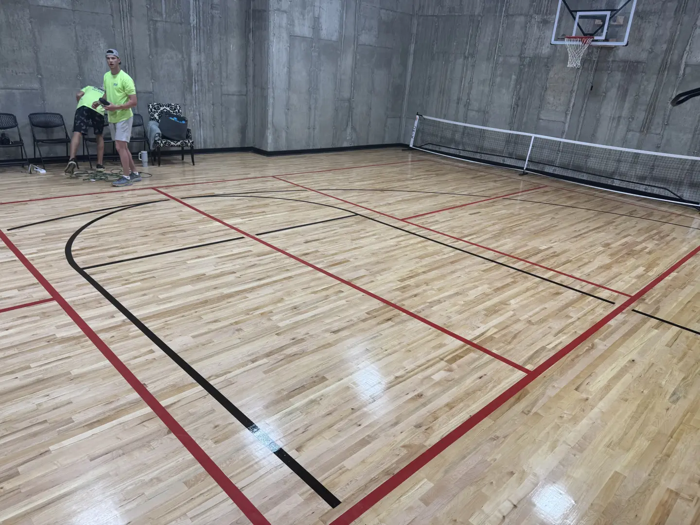 Indoor pickleball court with wooden floor and net