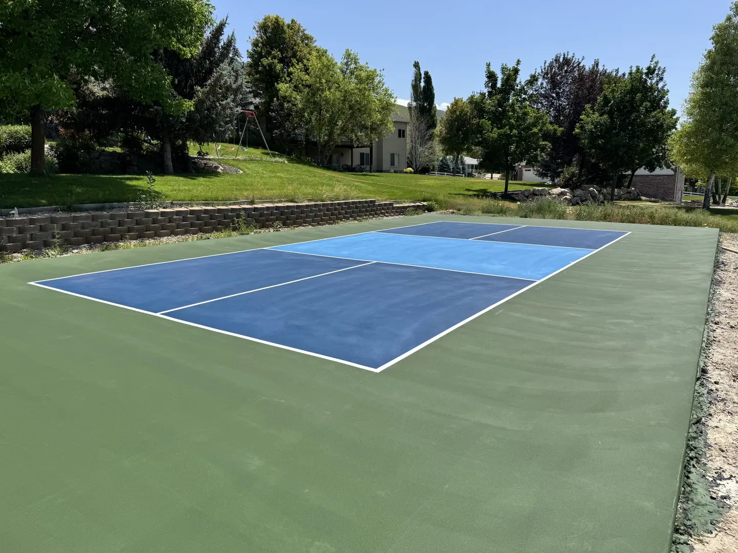 Newly painted blue and green pickleball court with white lines.