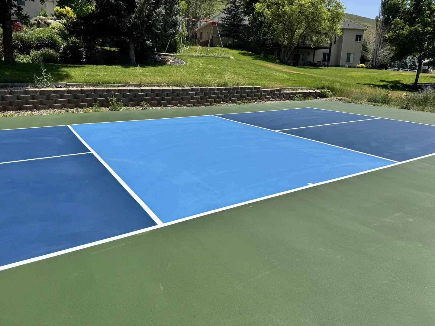 Newly painted blue and green pickleball court with white lines.