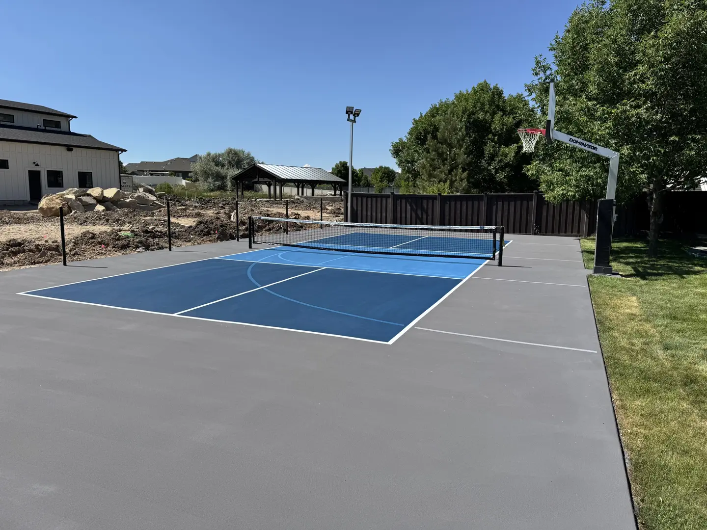 New pickleball court with basketball hoop and gazebo in backyard.