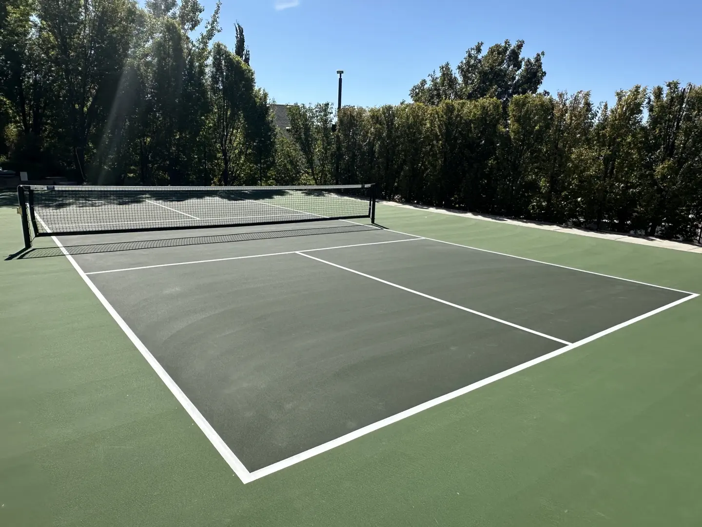 Outdoor tennis court with green surface and white lines