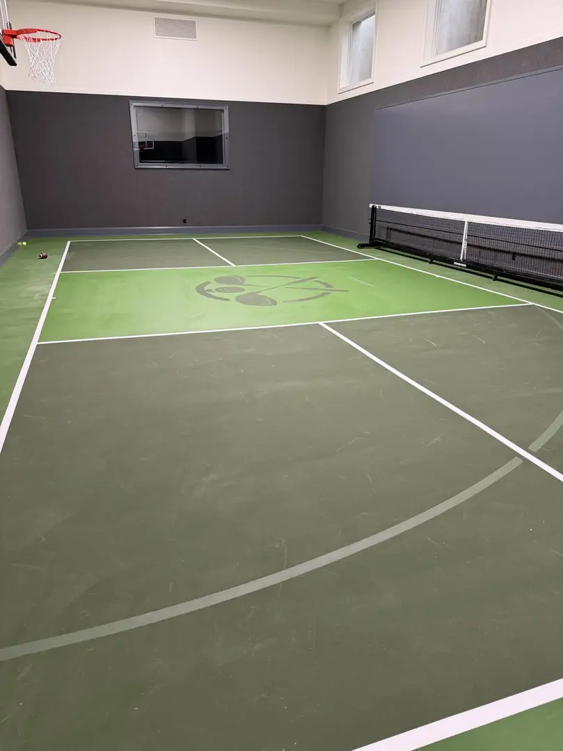 Indoor multi-sport court with basketball hoop and pickleball net