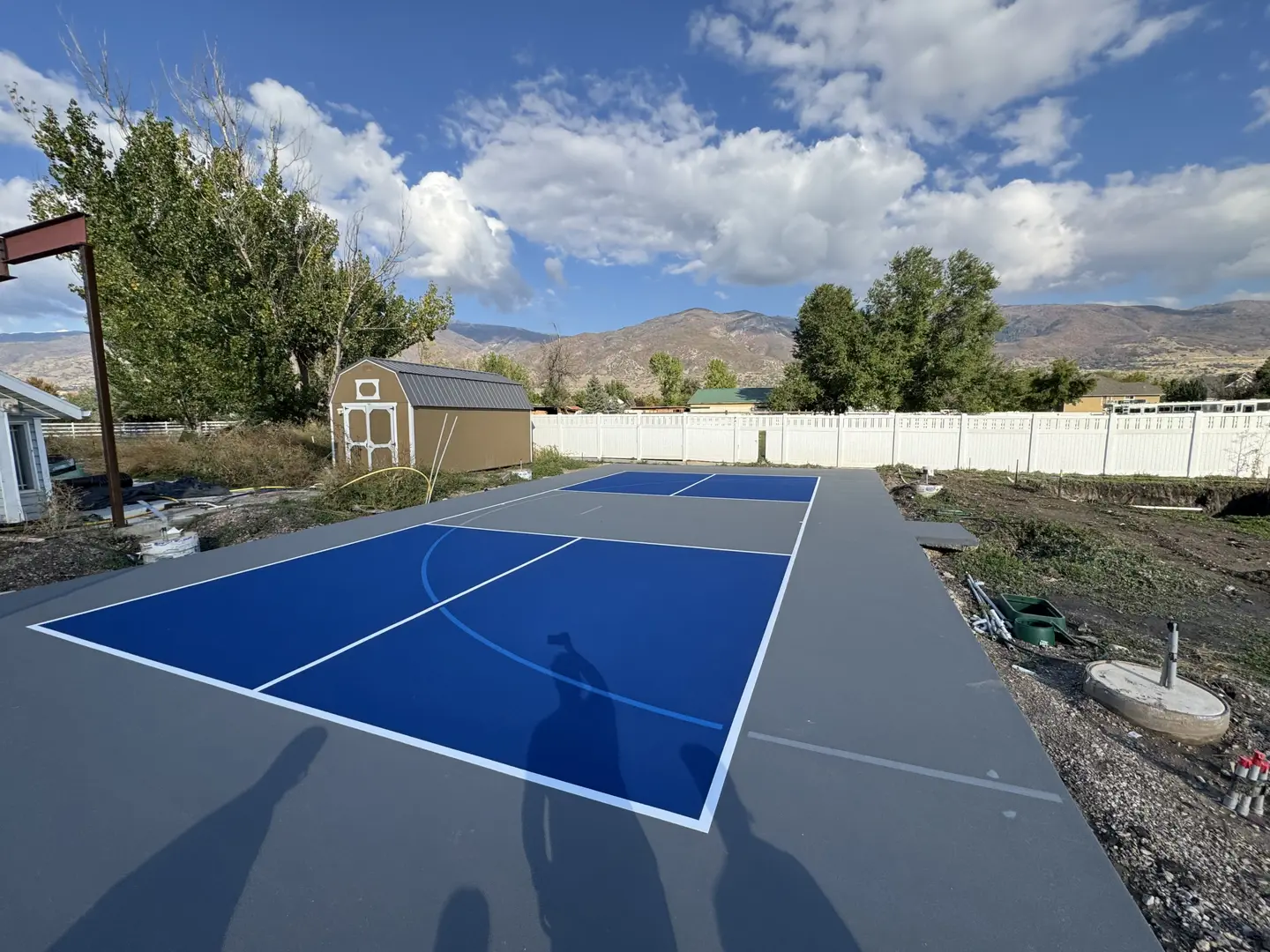 Newly painted blue and grey pickleball court with mountains in the background.