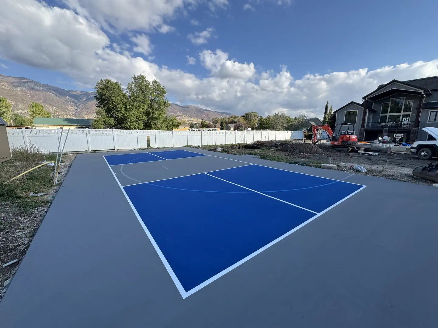 Newly painted blue and gray basketball court with white lines.