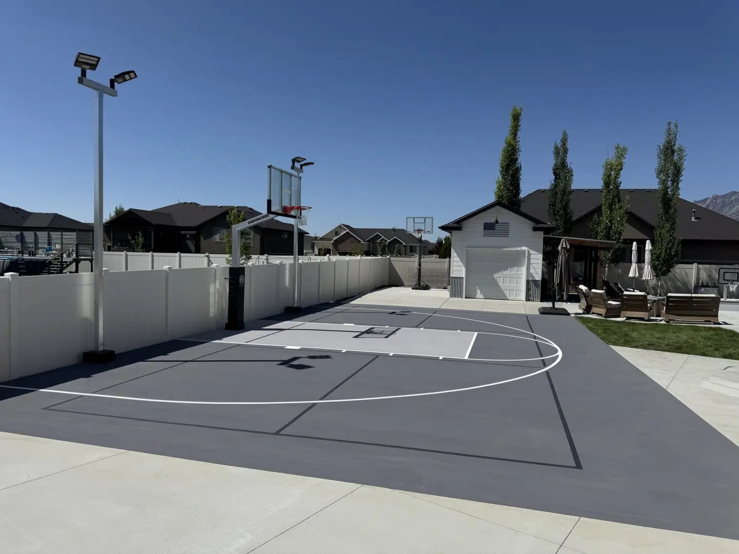 Modern backyard basketball court with lighting and a garage.