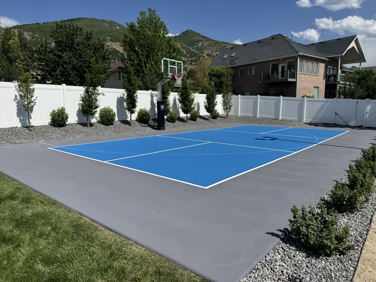Vibrant blue backyard basketball court with white lines.