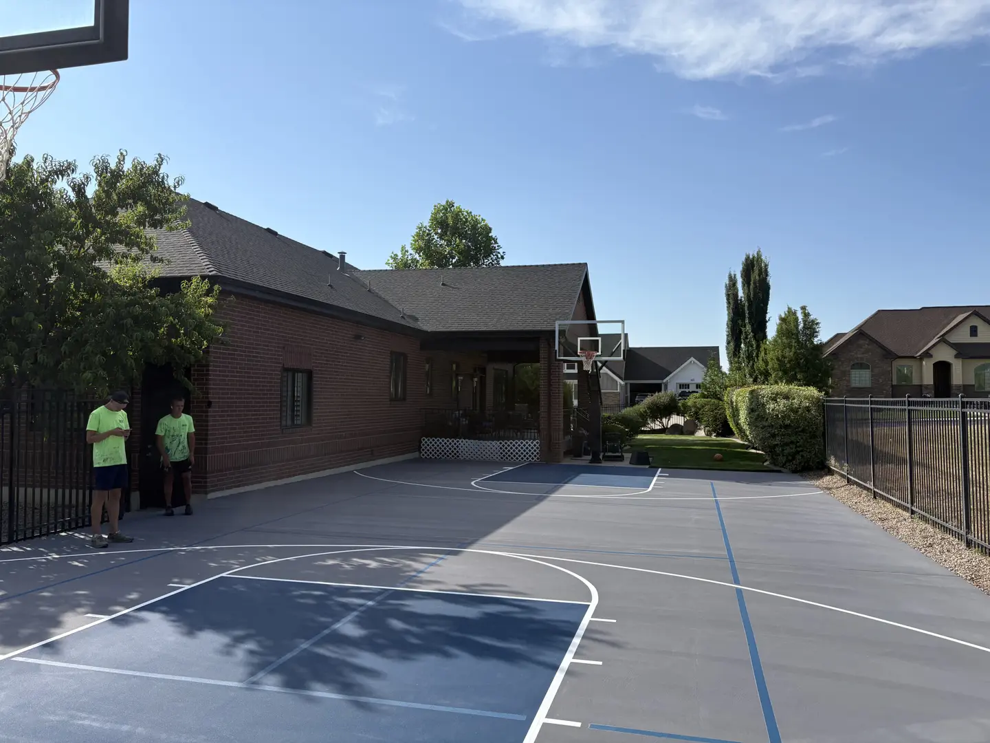 Backyard basketball court with two boys, blue and gray court.