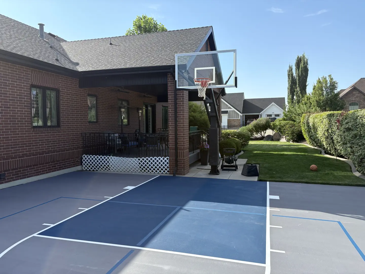 Custom backyard basketball court with blue and gray surfacing.