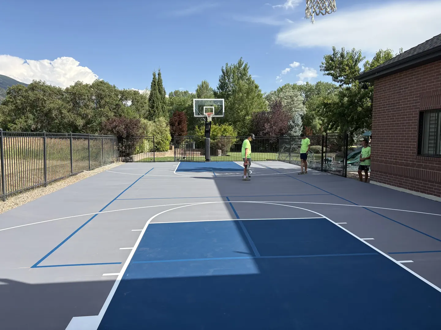 New backyard basketball court with blue and gray surfacing.
