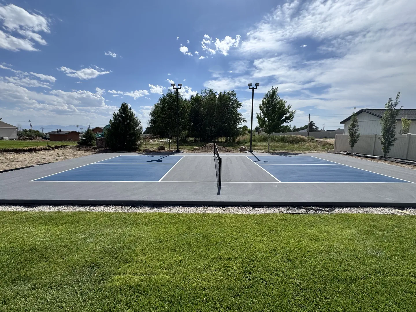 Newly constructed pickleball court with blue playing surface and lighting.