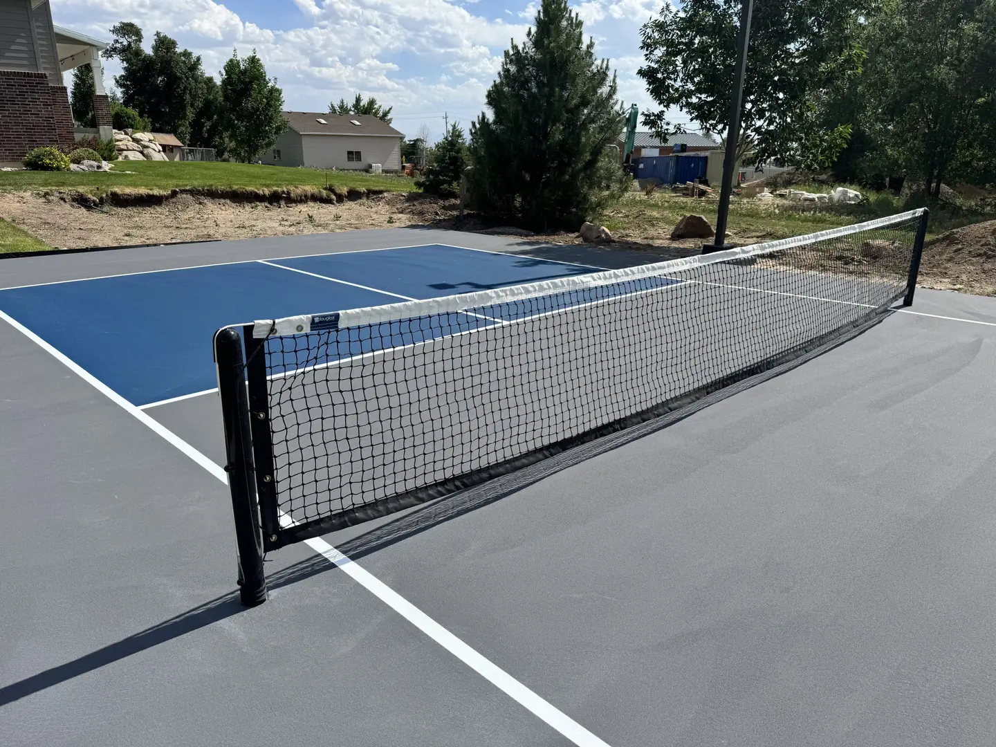 Newly painted blue and gray pickleball court with net