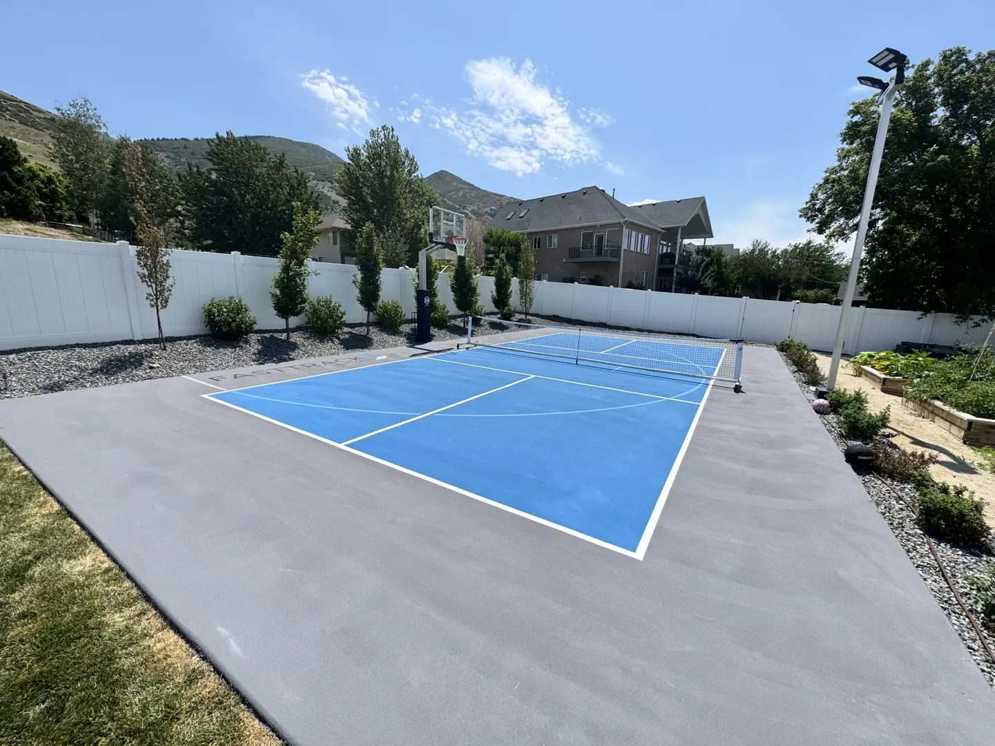 Blue multi-sport court with basketball hoop and pickleball net