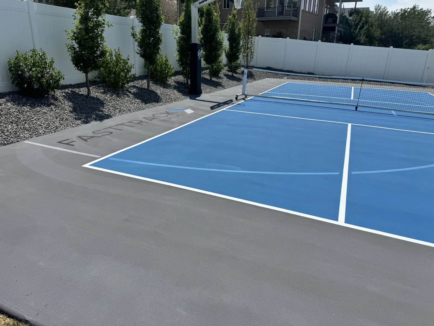 Newly painted blue pickleball court with white lines and "FASTTRACK" branding.