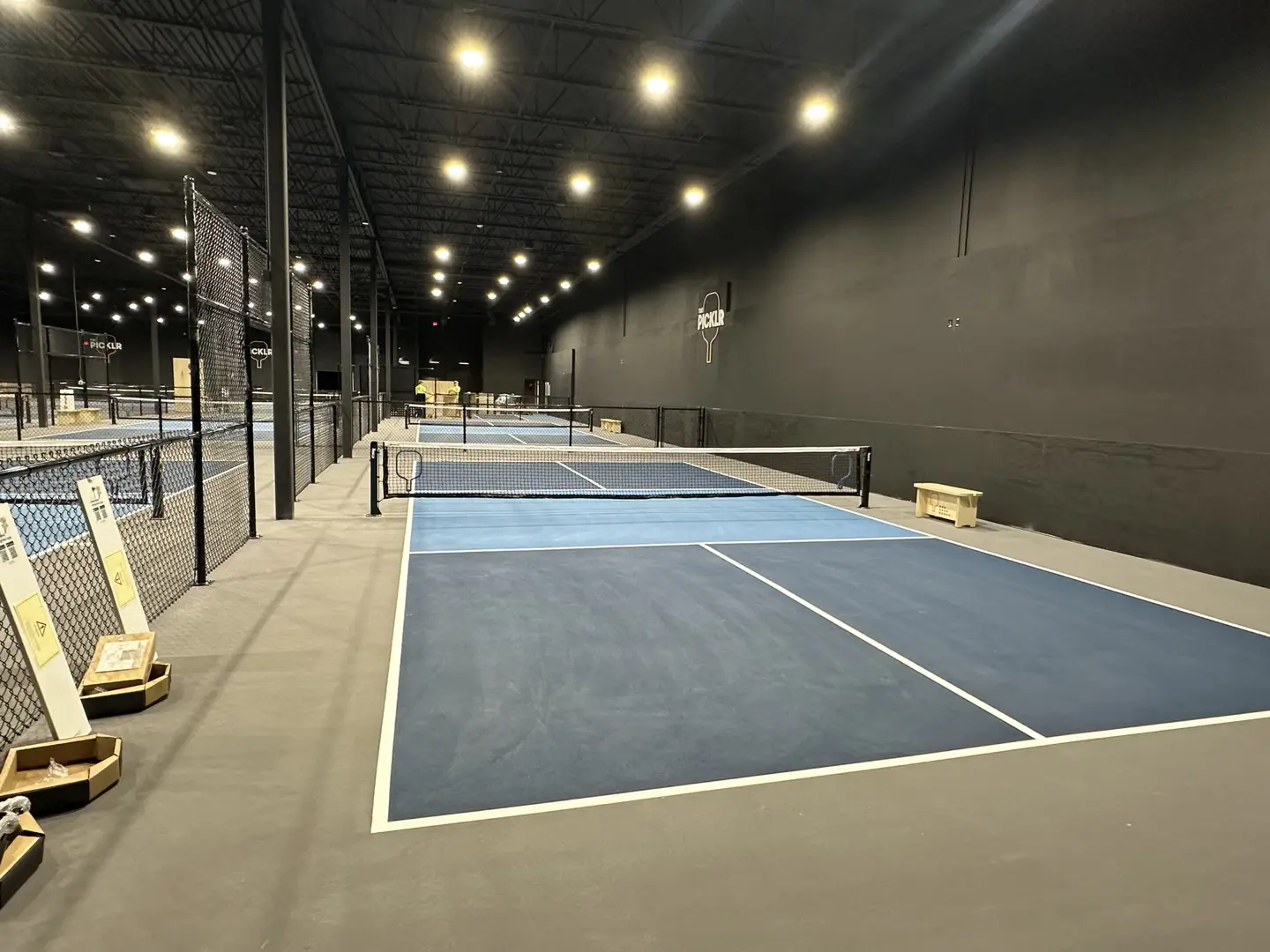 Indoor pickleball courts with blue surfaces and nets at Pickle Club.