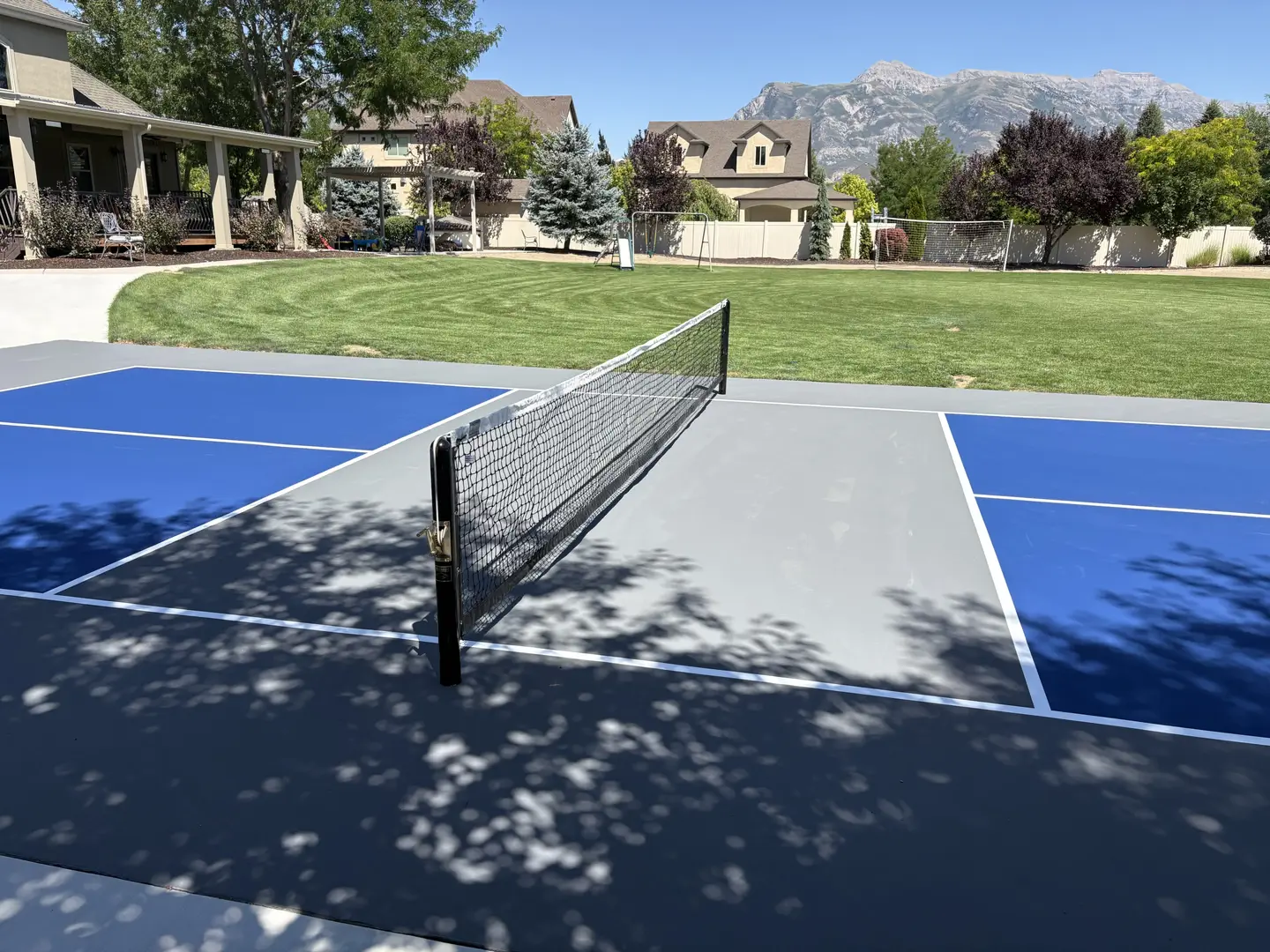 Blue and gray pickleball court with mountains in the background.