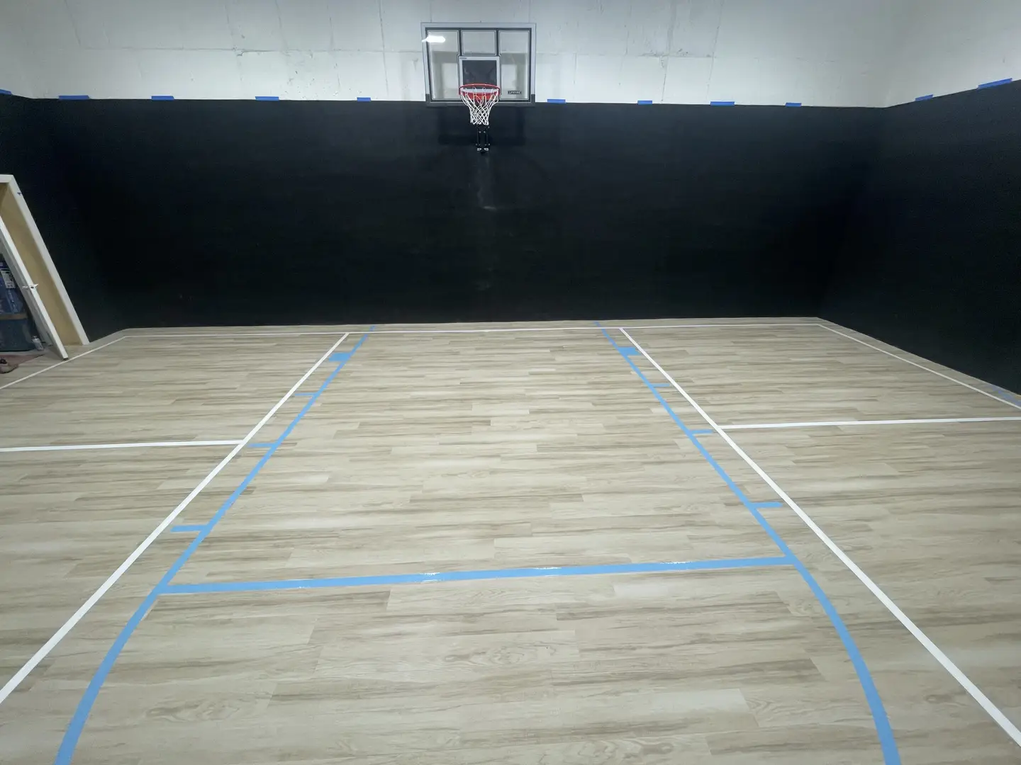 Indoor basketball court with wooden floor and black walls