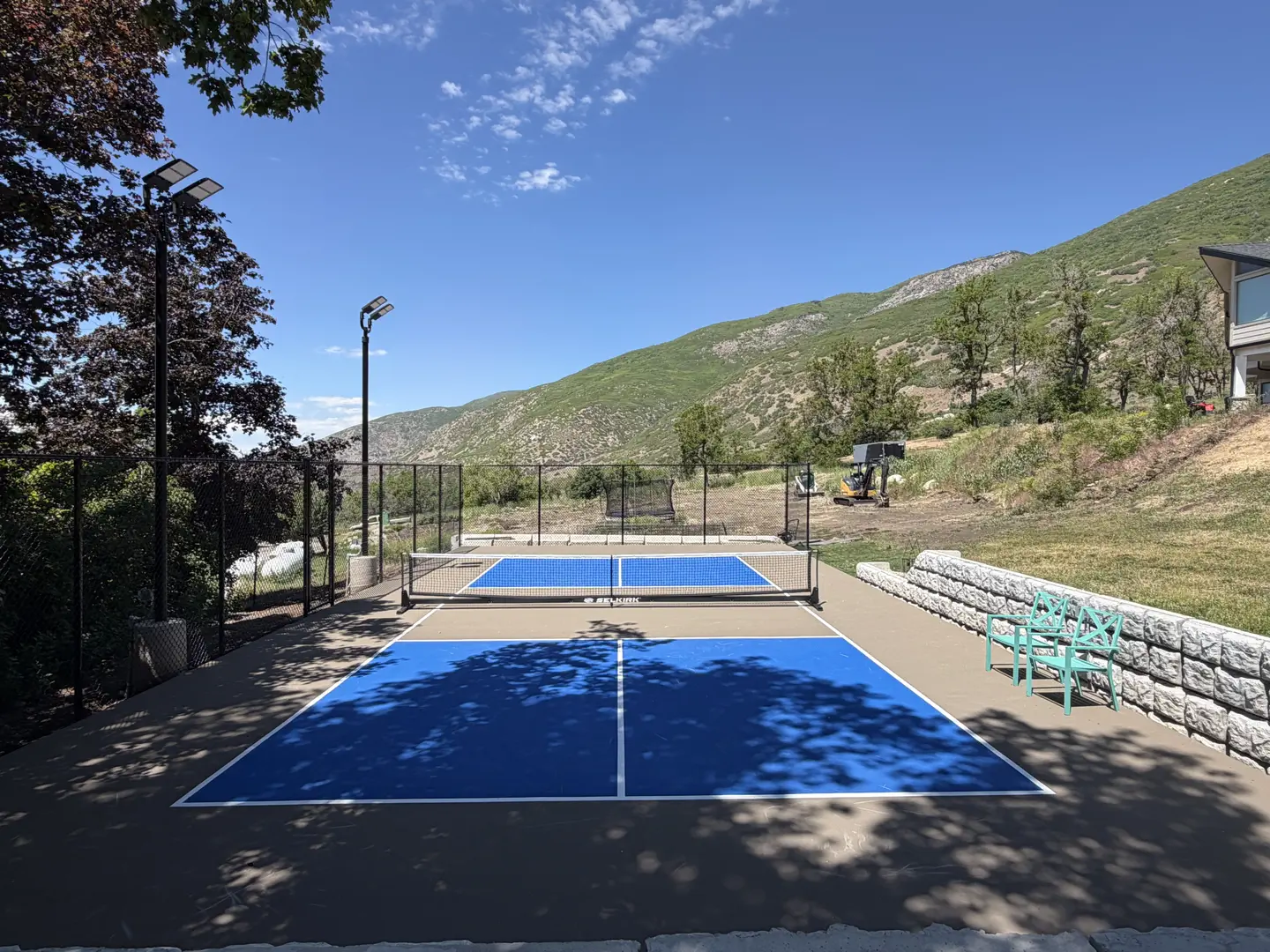 Vibrant blue pickleball courts with mountain backdrop and outdoor lighting.