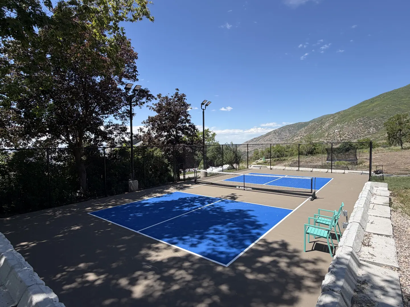Outdoor pickleball courts with blue playing surfaces and mountain backdrop