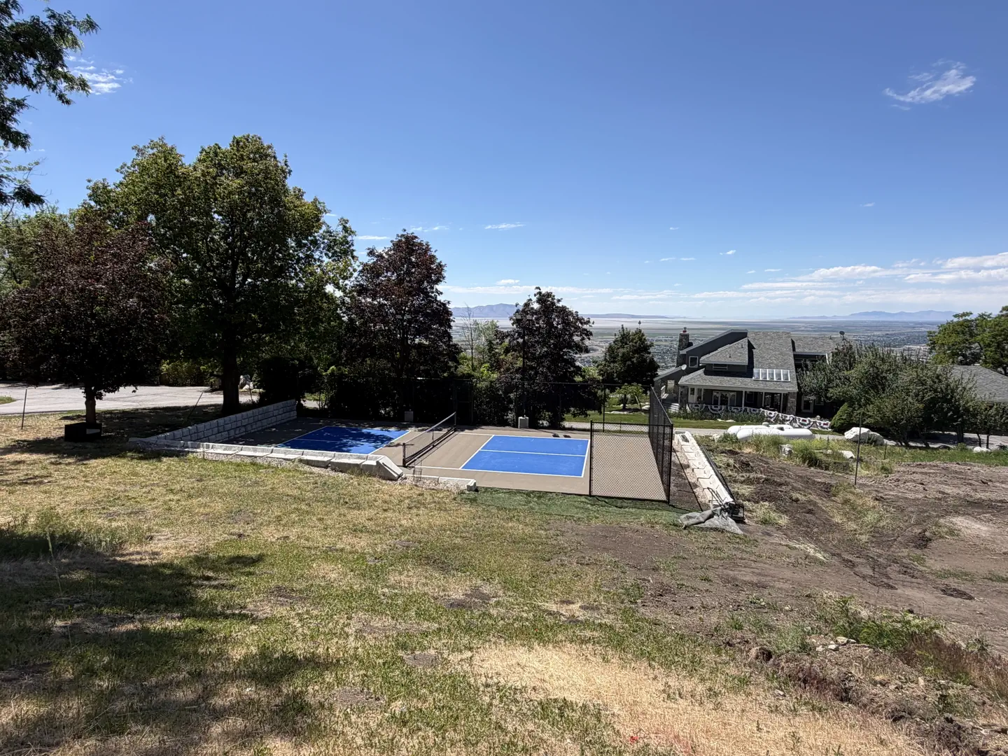 Blue pickleball courts with a scenic view of a valley and mountains.