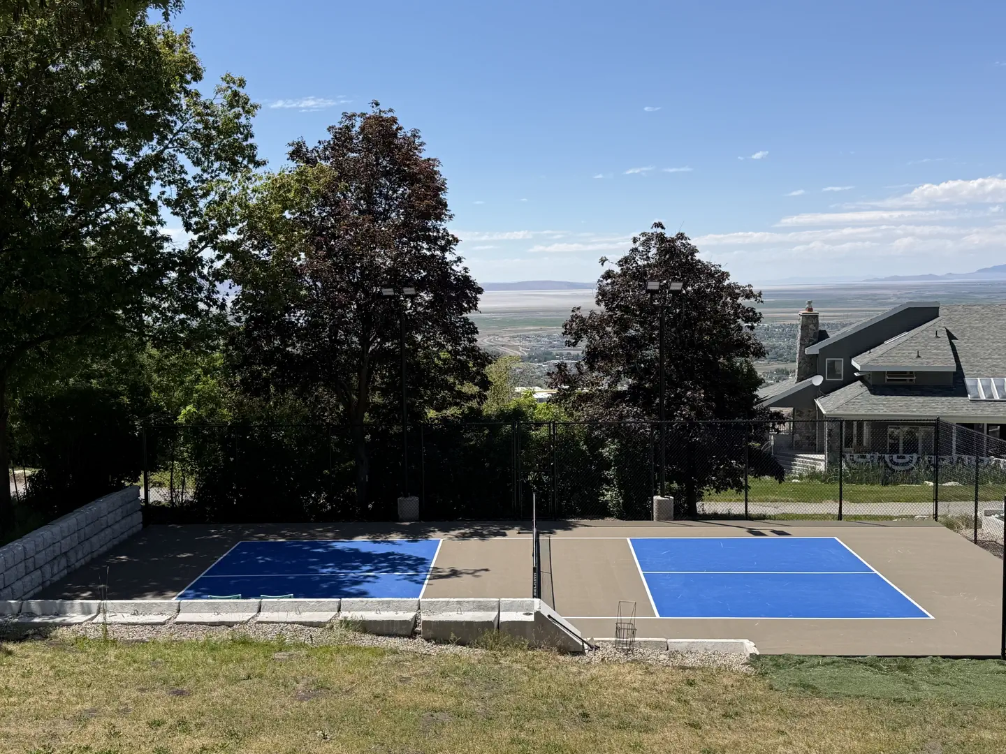 Outdoor pickleball court with blue playing surface and scenic view.