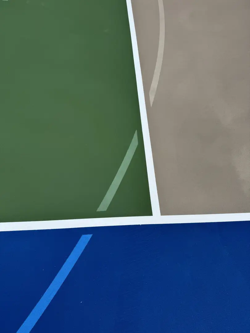 Abstract view of a sports court with green, tan, and blue sections.