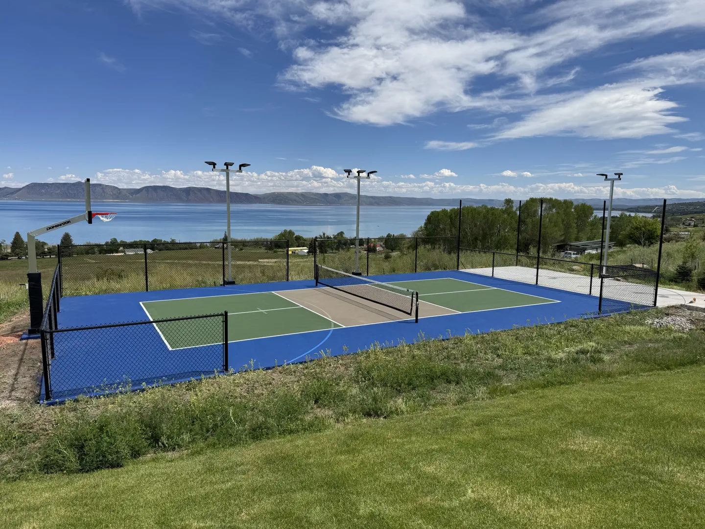 Pickleball court with basketball hoop overlooking a lake