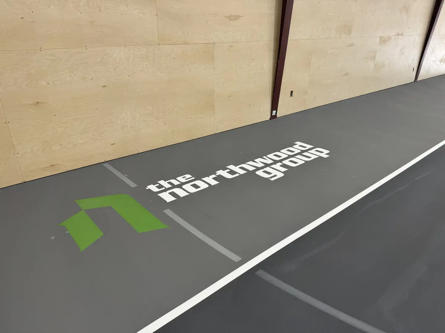 The Northwood Group logo on a grey floor with wooden walls.
