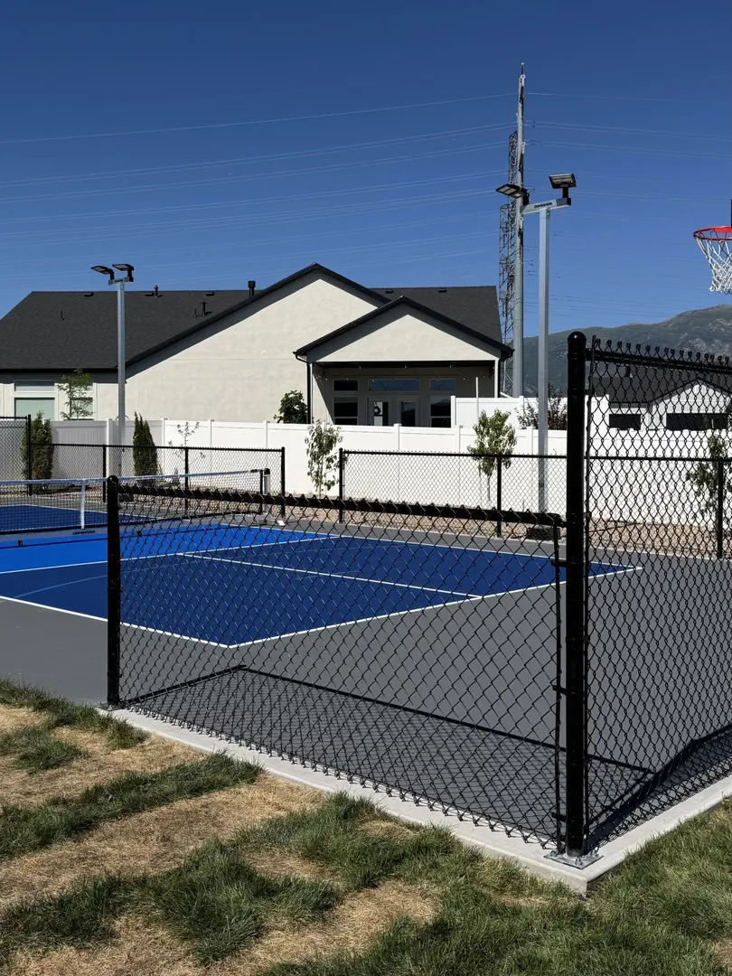 Modern pickleball court with blue and gray surface, fenced in.