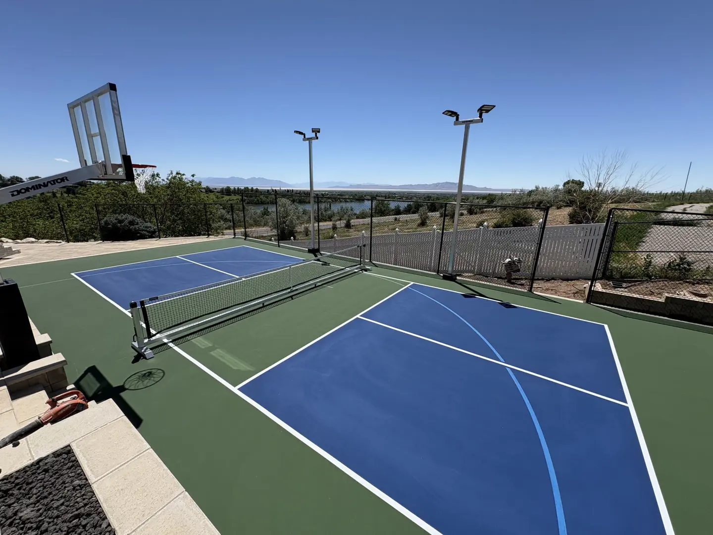 Outdoor pickleball court with basketball hoop and scenic view.