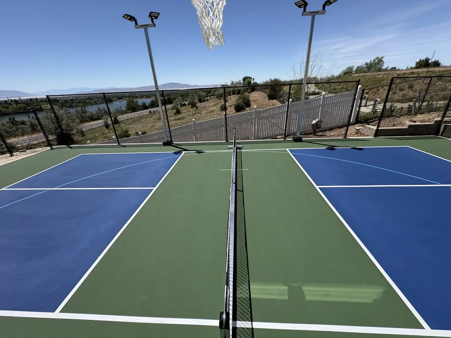 Outdoor pickleball court with blue and green surfacing and a net.