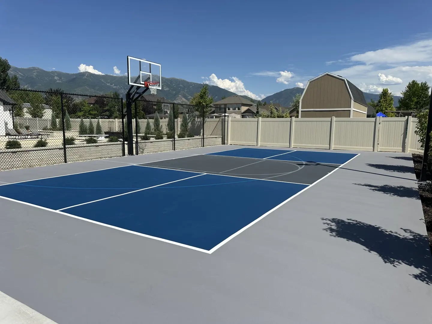 New multi-sport court with blue and grey surfacing and basketball hoop.