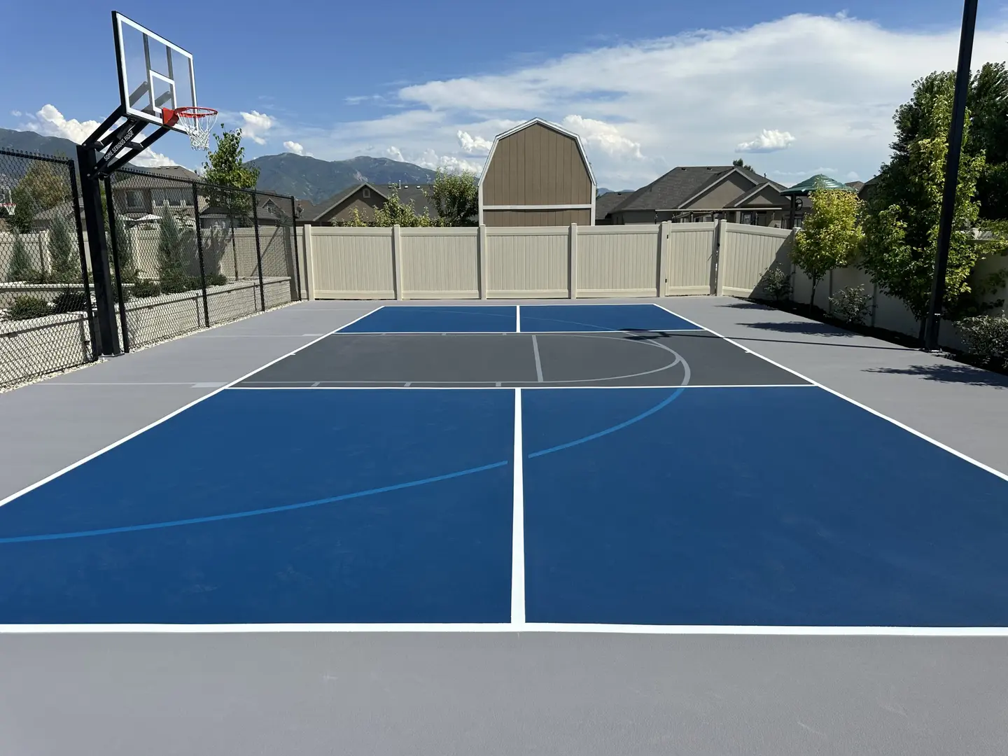Modern blue and gray basketball court with mountains in the background.