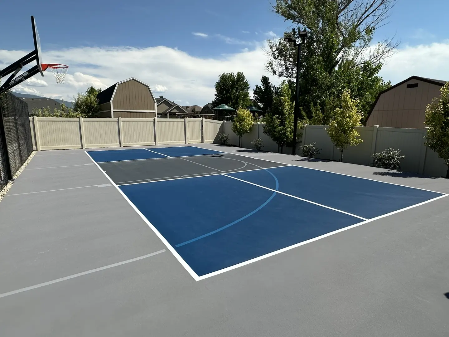 New multi-sport court with blue and grey surfacing and basketball hoop.