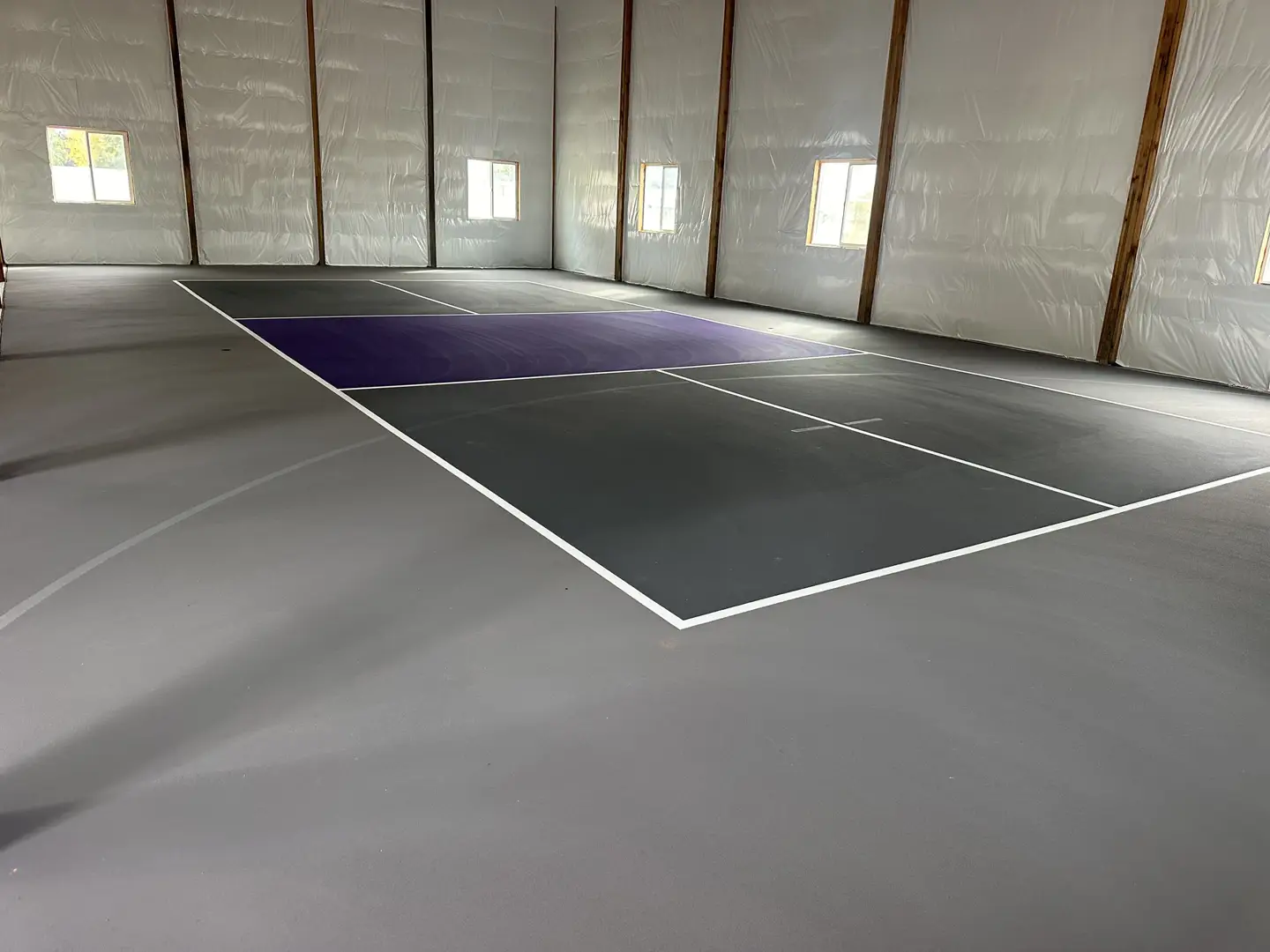 Indoor pickleball court with purple and gray playing surface.