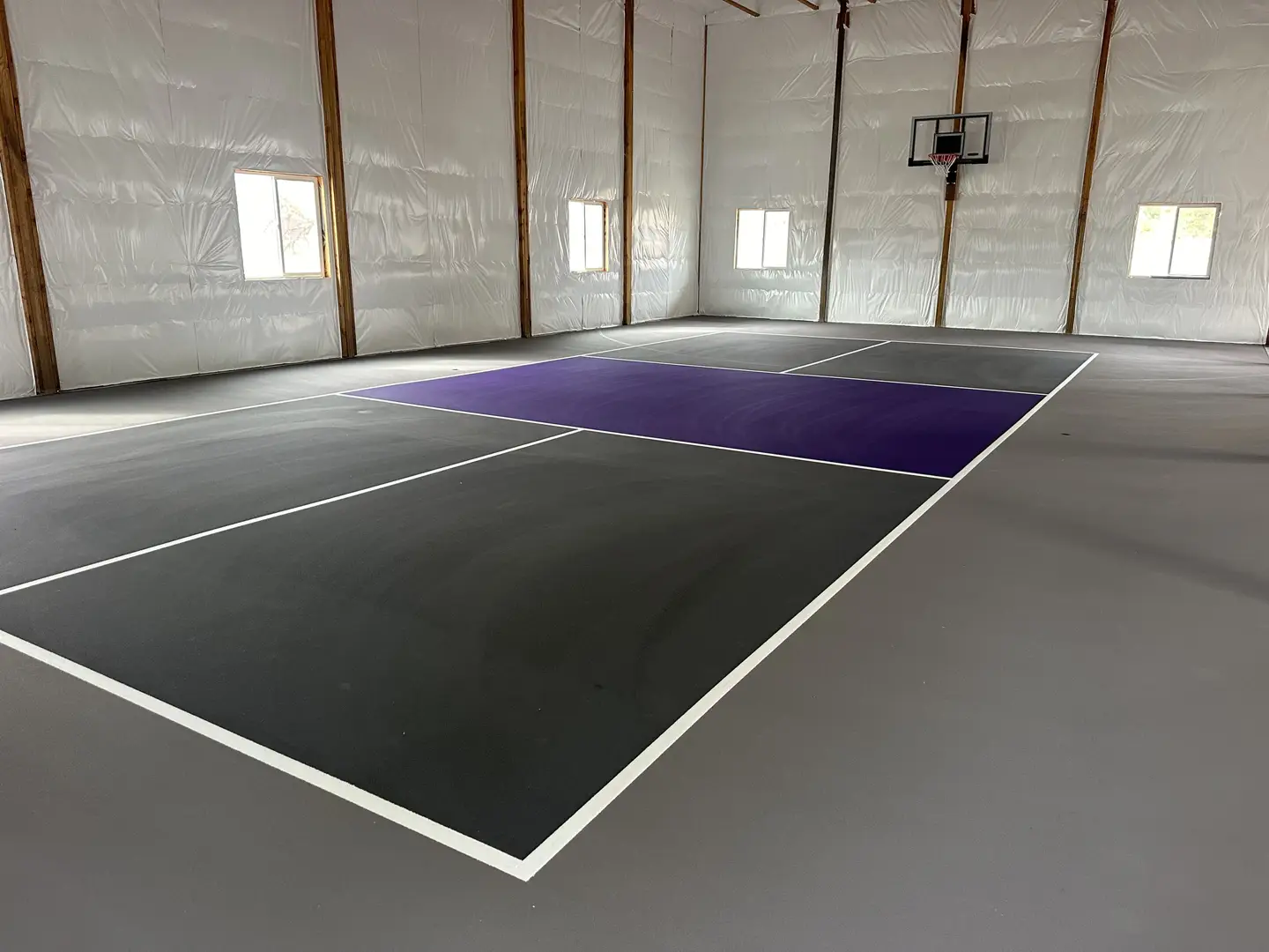 Indoor sports court with purple and gray sections and basketball hoop