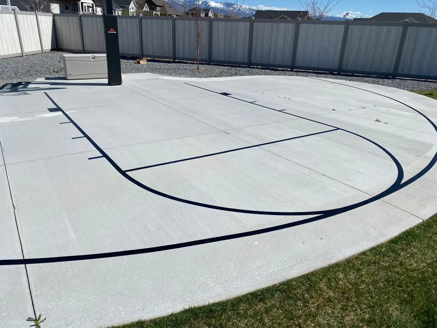 Newly painted basketball court lines on a concrete driveway.