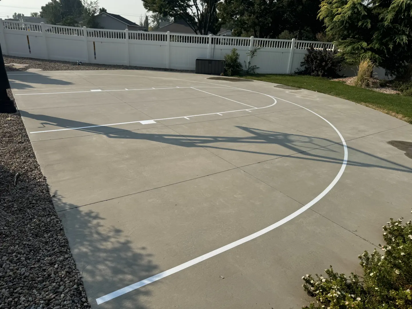 Newly painted basketball court lines on a concrete driveway.