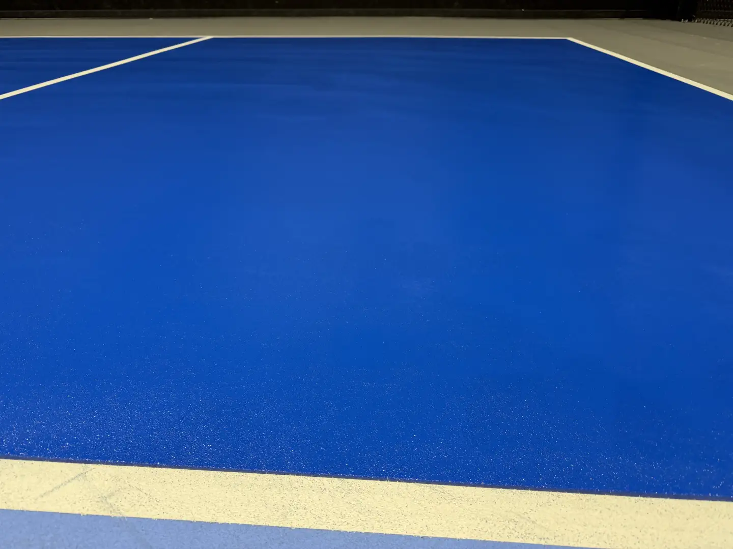Vibrant blue indoor sports court with white court lines.